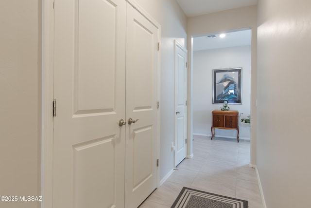 hallway with light tile patterned flooring, baseboards, and visible vents