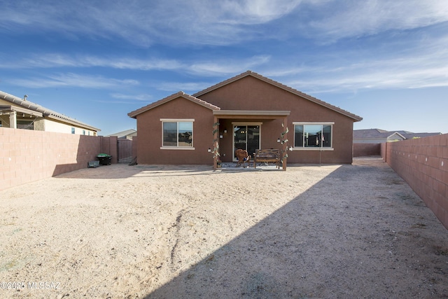 rear view of property featuring a patio, a fenced backyard, and stucco siding