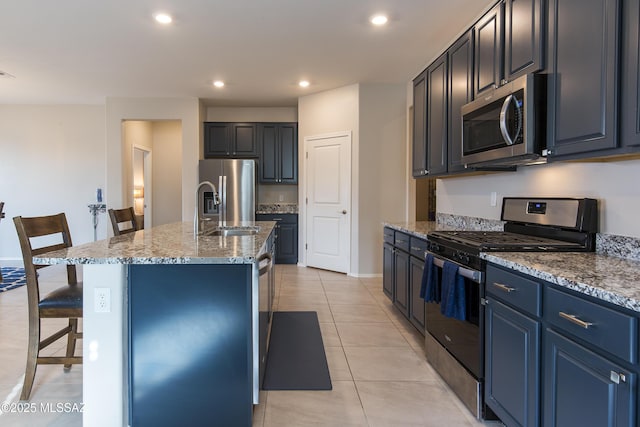 kitchen featuring light tile patterned flooring, a breakfast bar, stone countertops, a center island with sink, and stainless steel appliances