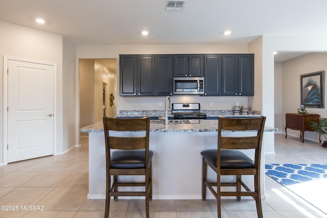 kitchen with a breakfast bar area, light stone countertops, appliances with stainless steel finishes, and visible vents