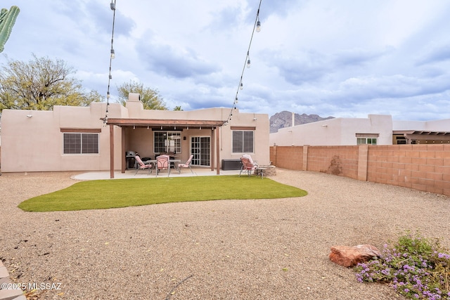 rear view of property with a fenced backyard, a patio area, and stucco siding