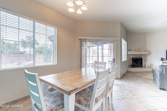 dining space with baseboards, light tile patterned floors, a notable chandelier, and a fireplace