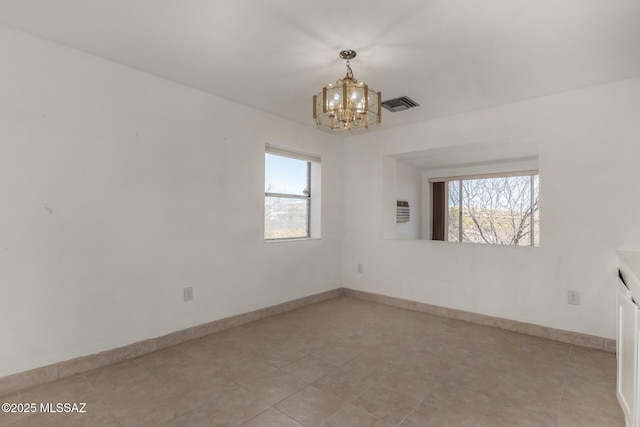 empty room with baseboards, visible vents, and a notable chandelier