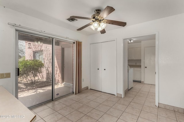 unfurnished bedroom with independent washer and dryer, light tile patterned flooring, access to exterior, visible vents, and a closet