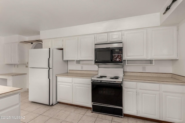 kitchen with black microwave, light countertops, freestanding refrigerator, electric stove, and white cabinetry
