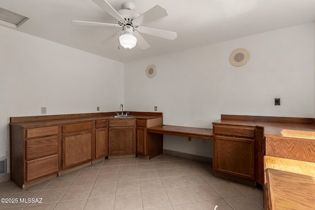 unfurnished office with visible vents, baseboards, ceiling fan, a sink, and light tile patterned floors