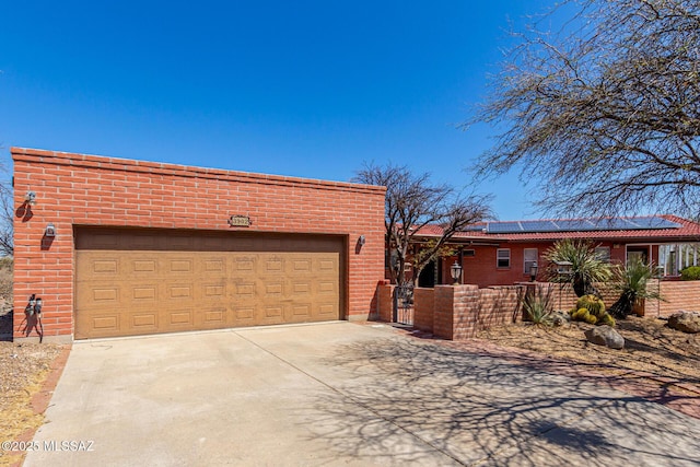 view of front of property featuring driveway, a fenced front yard, solar panels, a gate, and an attached garage