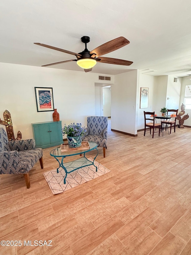 living room with baseboards, ceiling fan, visible vents, and light wood-style flooring