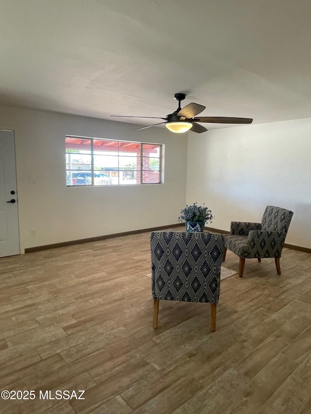 living area featuring baseboards, ceiling fan, and wood finished floors