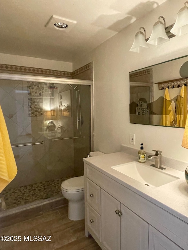 full bathroom featuring vanity, a stall shower, toilet, and wood finished floors