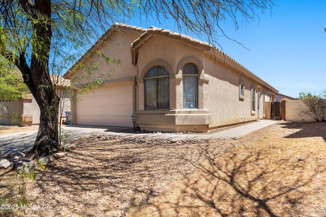 view of front of home featuring an attached garage, a gate, stucco siding, and driveway