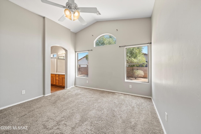 spare room with ceiling fan, visible vents, arched walkways, high vaulted ceiling, and carpet flooring