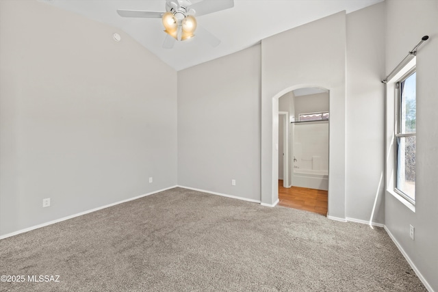 unfurnished bedroom with baseboards, carpet flooring, arched walkways, and multiple windows