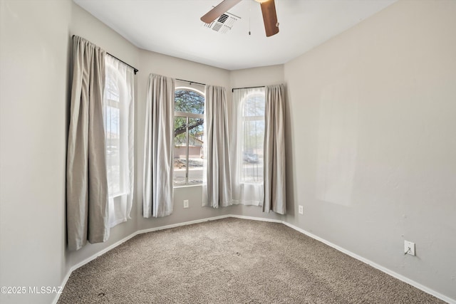 carpeted empty room featuring visible vents, a ceiling fan, and baseboards