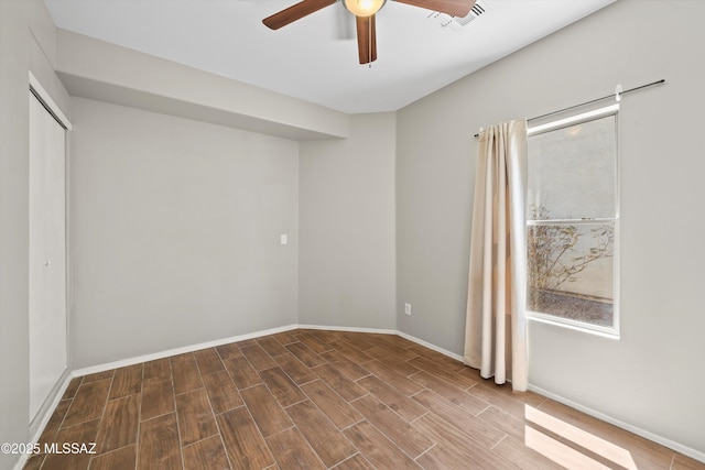 spare room with a ceiling fan, baseboards, visible vents, and wood finished floors