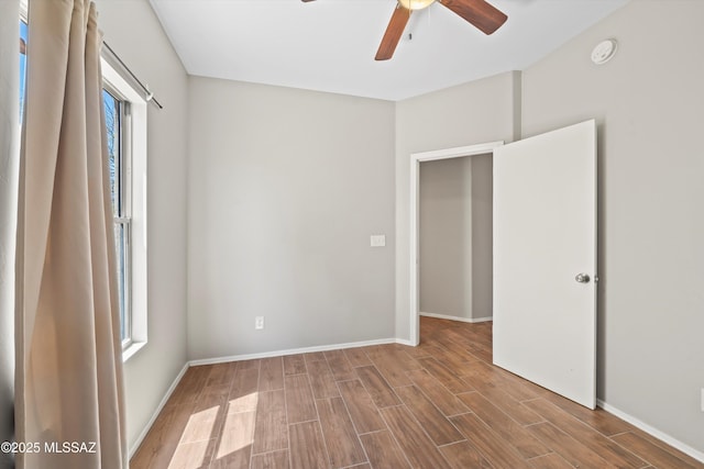 empty room featuring baseboards, ceiling fan, and wood finished floors