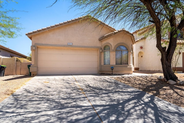 view of front of property featuring fence, a tile roof, a garage, stucco siding, and concrete driveway