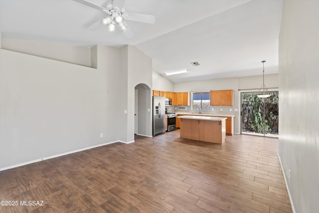 kitchen with appliances with stainless steel finishes, light countertops, open floor plan, a kitchen island, and visible vents
