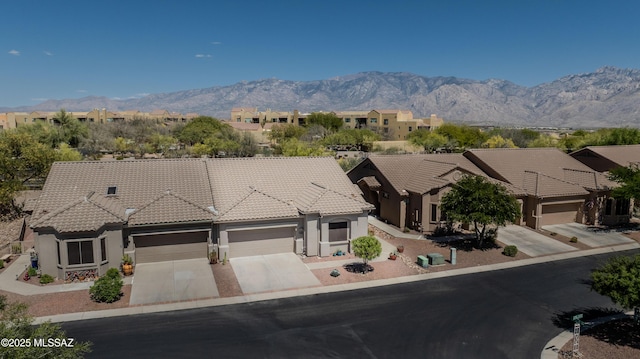 view of front of property with a garage, stucco siding, a tiled roof, a mountain view, and driveway