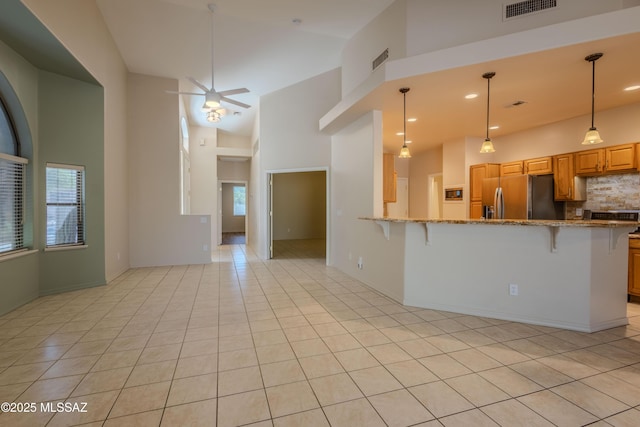 kitchen with ceiling fan, a high ceiling, stainless steel refrigerator with ice dispenser, and visible vents
