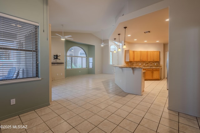 kitchen with a ceiling fan, decorative backsplash, light tile patterned floors, lofted ceiling, and a kitchen bar