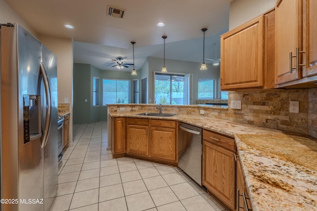 kitchen with a peninsula, tasteful backsplash, a sink, appliances with stainless steel finishes, and light tile patterned floors