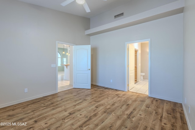 unfurnished bedroom with visible vents, baseboards, ensuite bathroom, and wood finished floors