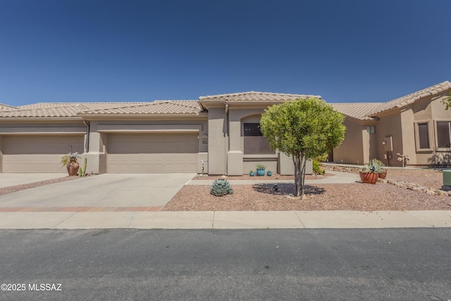 view of front of property featuring concrete driveway, a tiled roof, stucco siding, and a garage