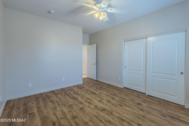 unfurnished bedroom with baseboards, ceiling fan, wood finished floors, and a closet