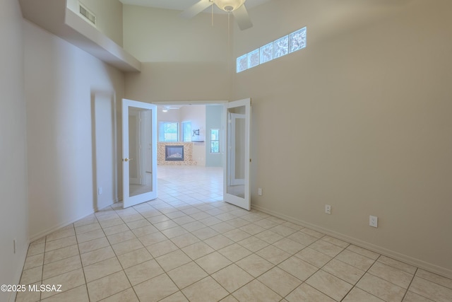 spare room with a ceiling fan, french doors, visible vents, light tile patterned floors, and a high ceiling