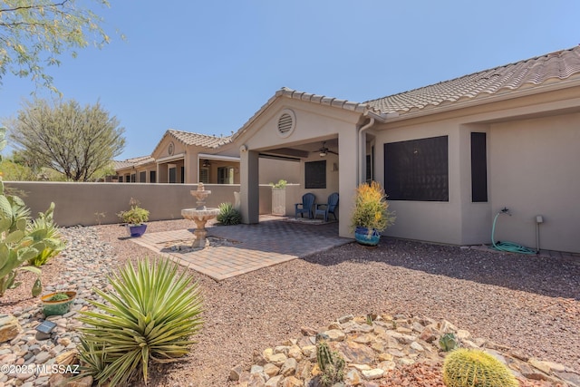 back of property featuring fence, stucco siding, a ceiling fan, a patio area, and a tiled roof
