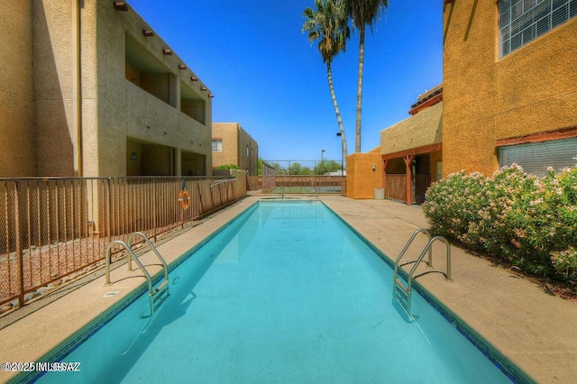 community pool with a patio and a fenced backyard