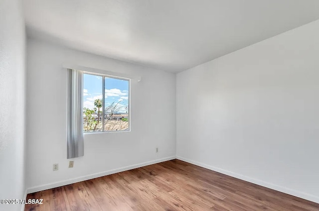 empty room with baseboards and wood finished floors