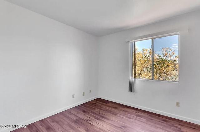 spare room featuring baseboards and wood finished floors