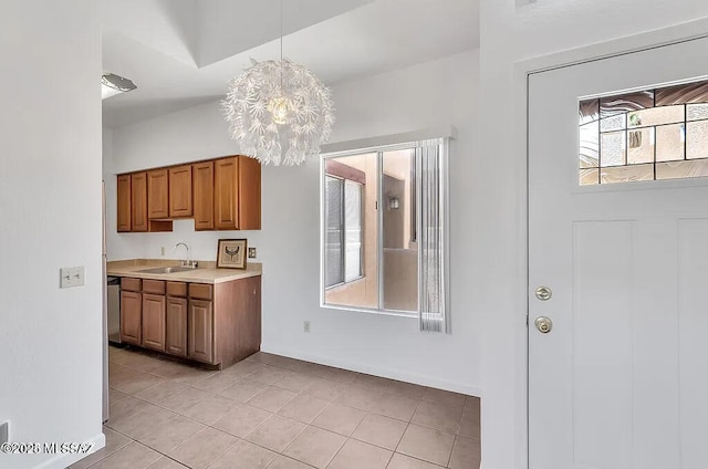 kitchen with brown cabinets, a sink, light countertops, light tile patterned floors, and pendant lighting