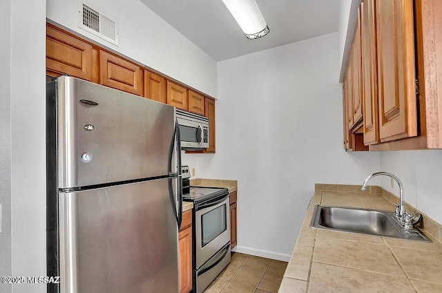 kitchen featuring tile countertops, visible vents, appliances with stainless steel finishes, a sink, and light tile patterned floors