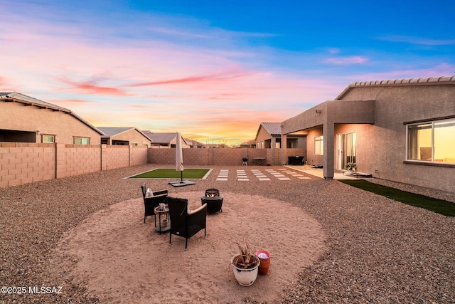 yard at dusk with a fenced backyard, a patio, and a fire pit
