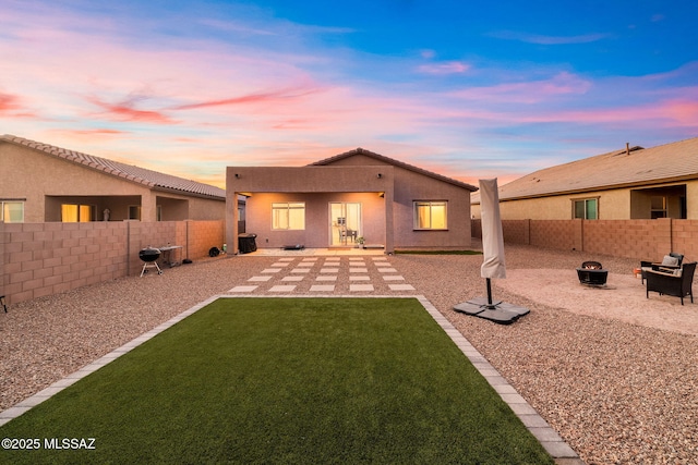 rear view of property featuring an outdoor fire pit, stucco siding, and a patio area