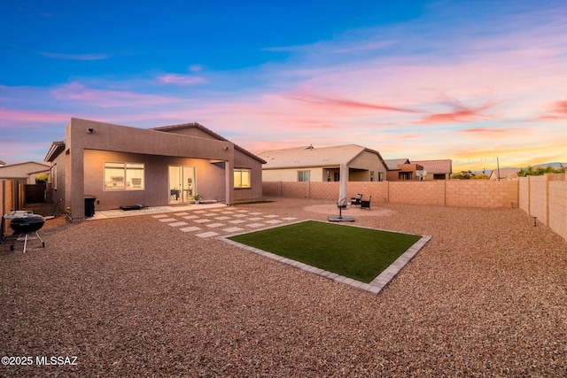 back of house featuring a fenced backyard, a patio, and stucco siding