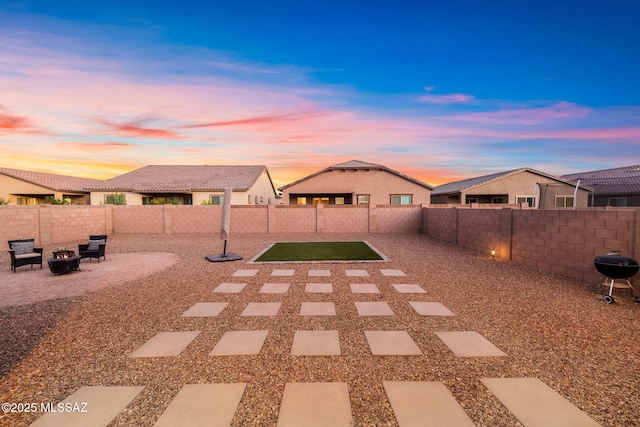 yard at dusk featuring a fire pit, a fenced backyard, and a patio