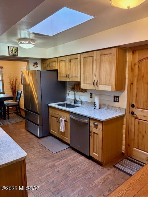 215 E Los Rincones, Green Valley, AZ 85614 - kitchen with brown cabinetry, dark wood-style flooring, a skylight, a sink, and stainless steel appliances