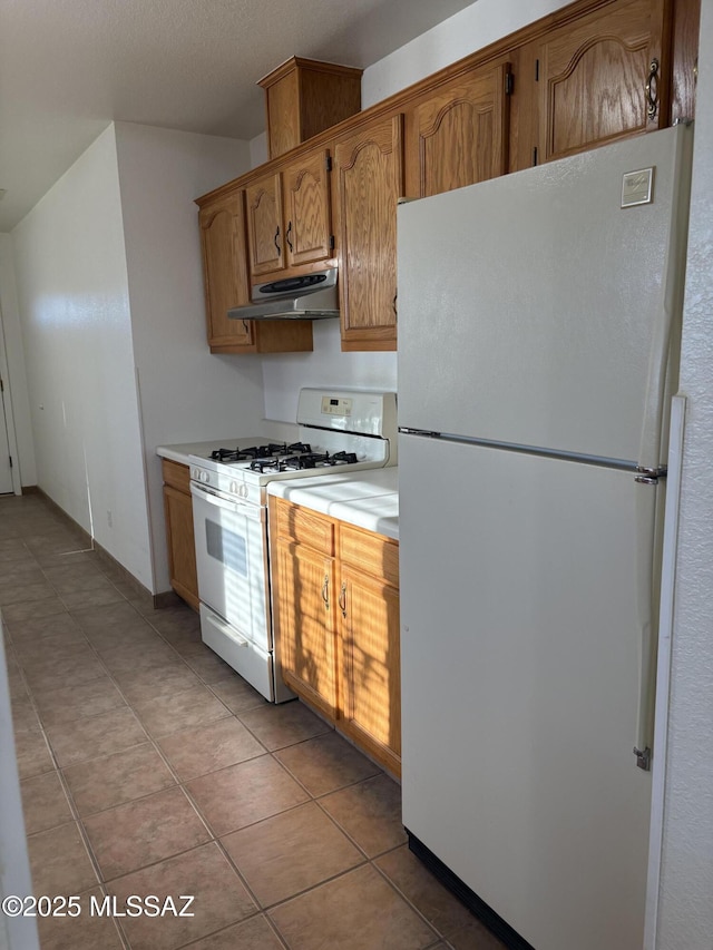 829 E Calle Esplendor, Nogales, AZ 85621 - kitchen with light tile patterned flooring, white appliances, light countertops, brown cabinetry, and under cabinet range hood