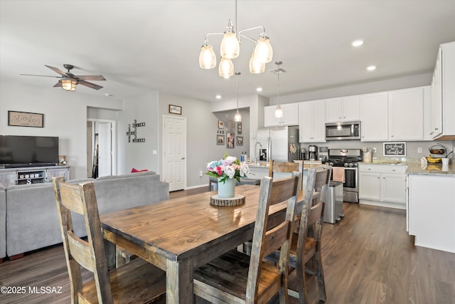 dining area with dark wood-style flooring, recessed lighting, and ceiling fan with notable chandelier