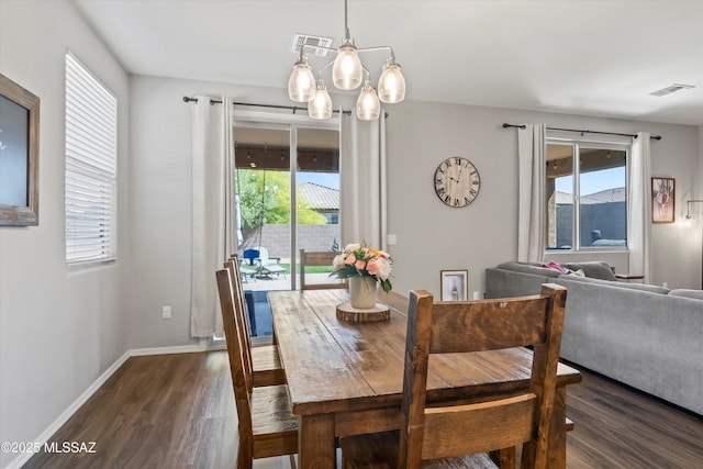 dining room featuring dark wood-style flooring, a chandelier, visible vents, and a wealth of natural light