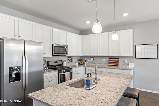 kitchen featuring baseboards, dark wood-style floors, white cabinets, a sink, and stainless steel appliances
