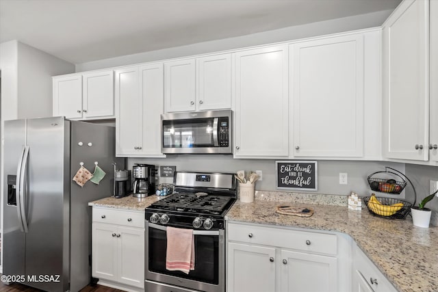 kitchen with white cabinetry, appliances with stainless steel finishes, and light stone counters