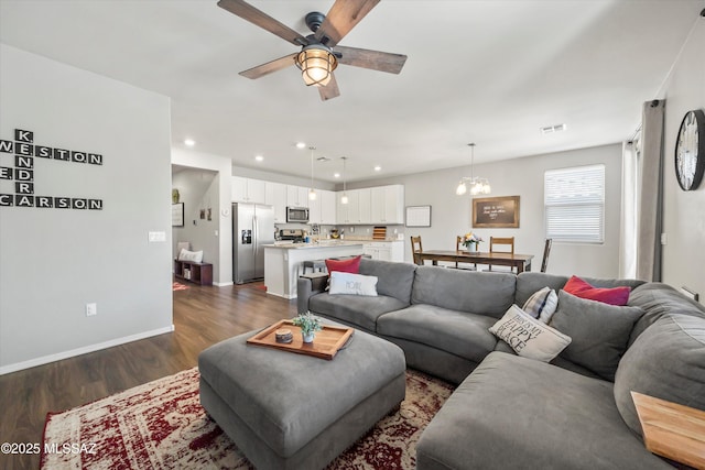 living room with visible vents, baseboards, recessed lighting, dark wood finished floors, and ceiling fan with notable chandelier