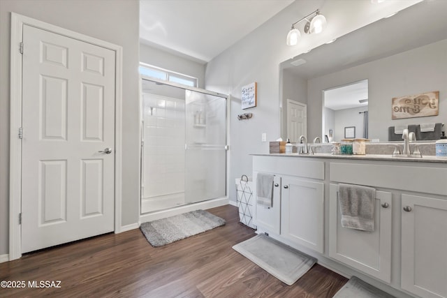 bathroom with a sink, double vanity, a shower stall, and wood finished floors