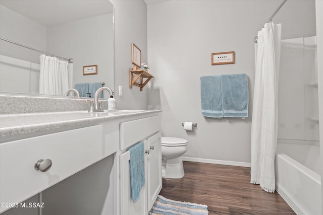 bathroom with vanity, wood finished floors, toilet, baseboards, and shower / bath combo