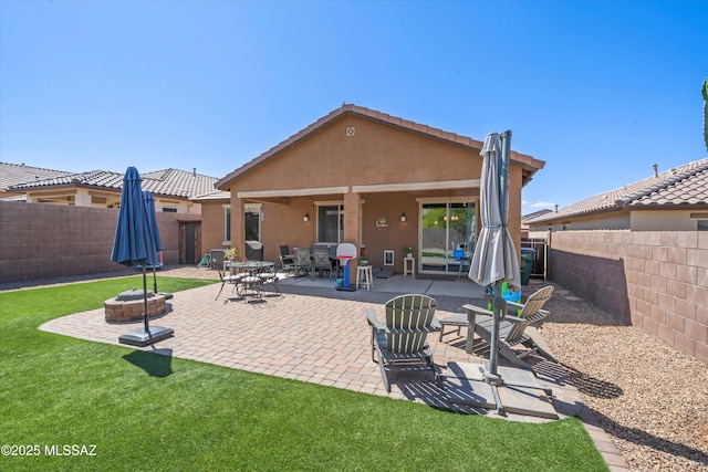 back of house featuring a fenced backyard, stucco siding, an outdoor fire pit, and a patio area